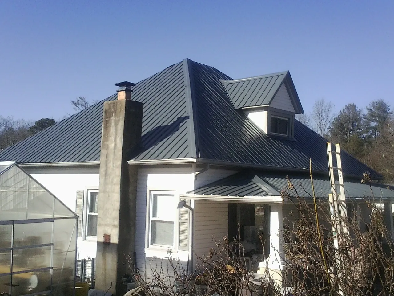 Dark blue standing seam metal roof on a white farmhouse with dormer — Slate & Tile Roof Repair by Roofing Brothers in Woodsfield
