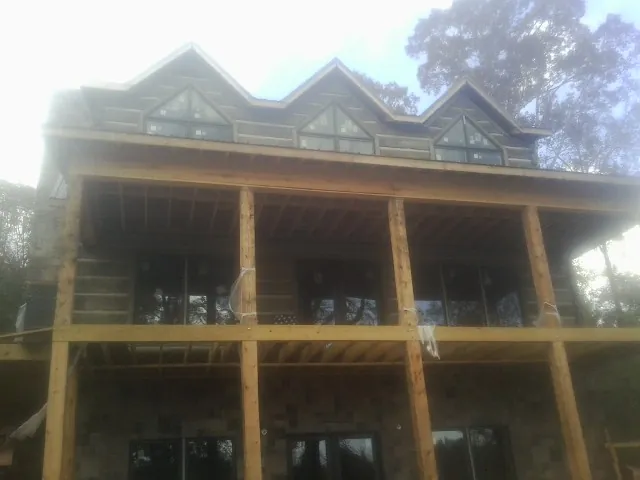 Dormers and porch framing on a large log home under construction — Roof Coating work by our crew in Woodsfield