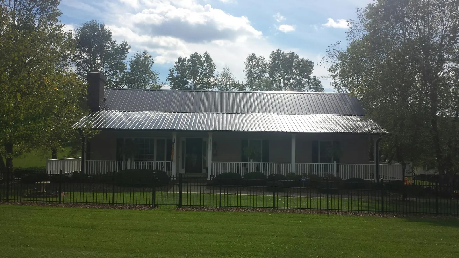 Gray metal roof on a brick ranch with a full width front porch — Gutter Guard Installation work by our crew in Woodsfield