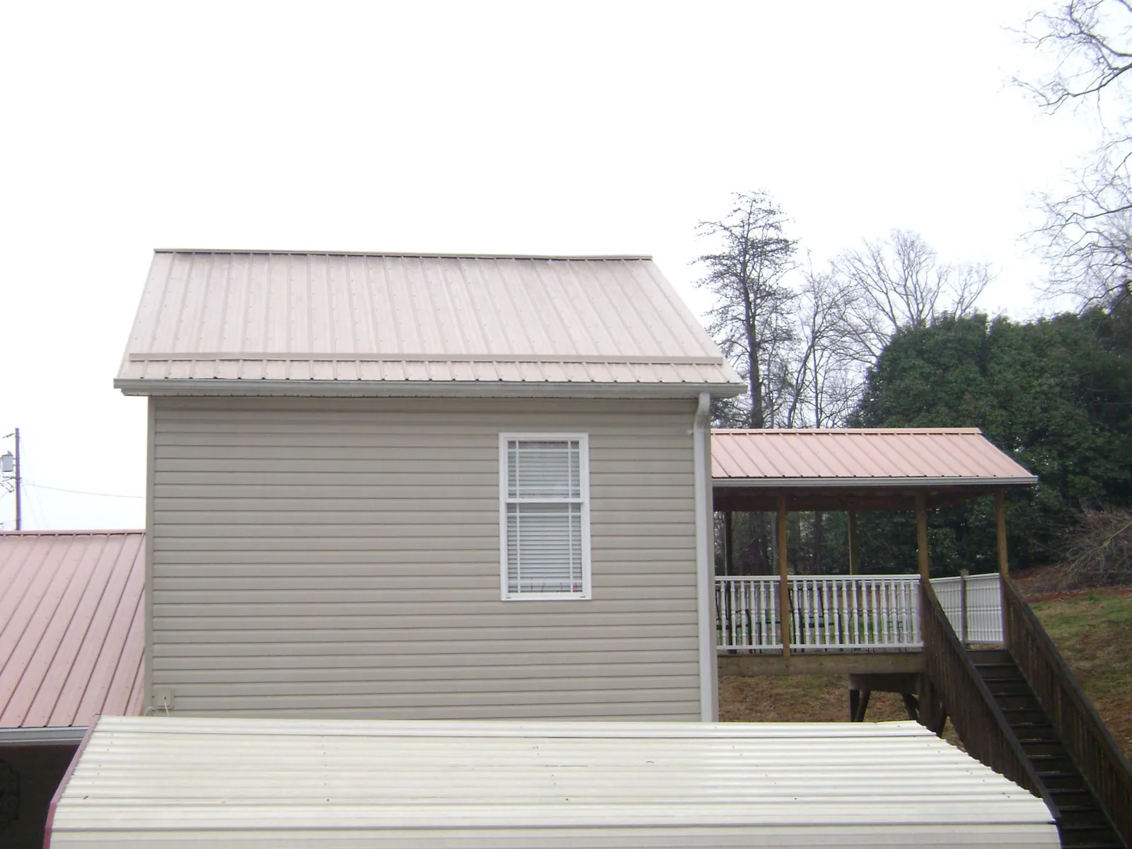 Tan metal roofs on a two story addition and attached porch, from a Roof Replacement job in Woodsfield