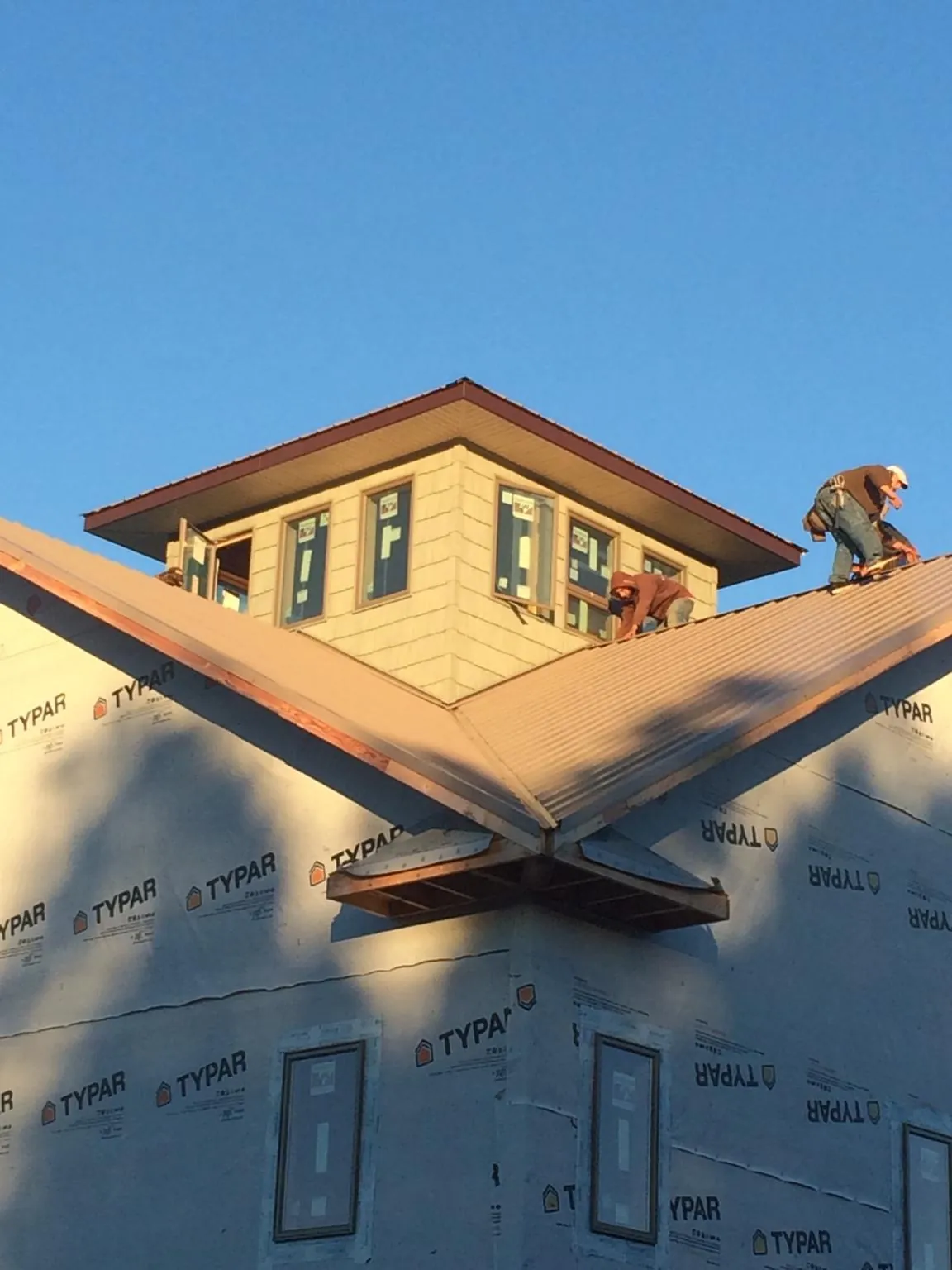 Roofers working around a rooftop cupola on a new metal roof at sunset — Roof Waterproofing in Woodsfield by Roofing Brothers